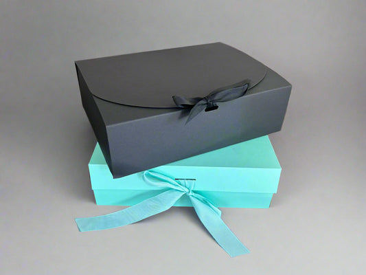 Two gift boxes, one black and one turquoise, with ribbons on a gray background