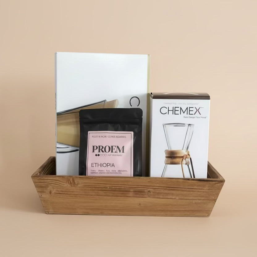 Coffee packaging including Proem coffee bag and Chemex product box in a wooden basket on a beige background
