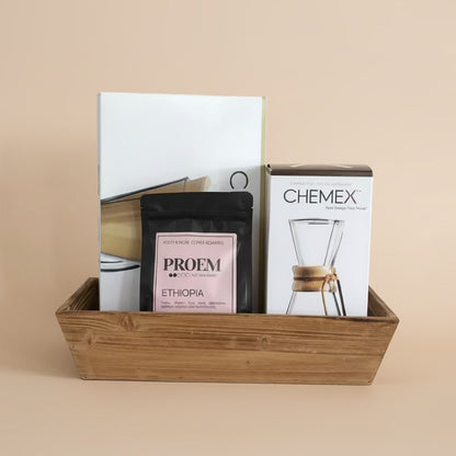 Coffee packaging including Proem coffee bag and Chemex product box in a wooden basket on a beige background