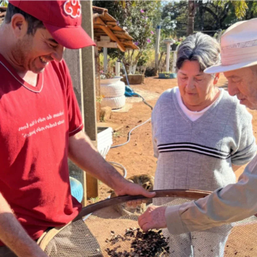 Three people, two adults and a child, are engaged in an outdoor activity involving a筛子 (screen) and soil.