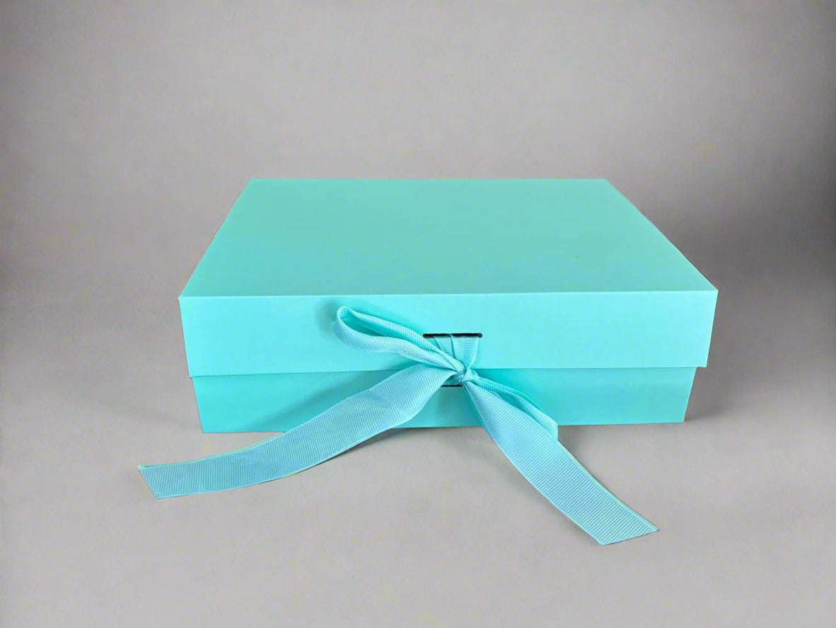 Turquoise gift box with a ribbon on a wooden surface