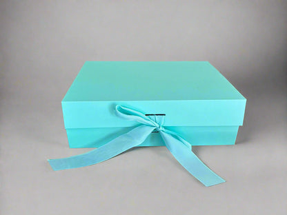 Turquoise gift box with a ribbon on a wooden surface